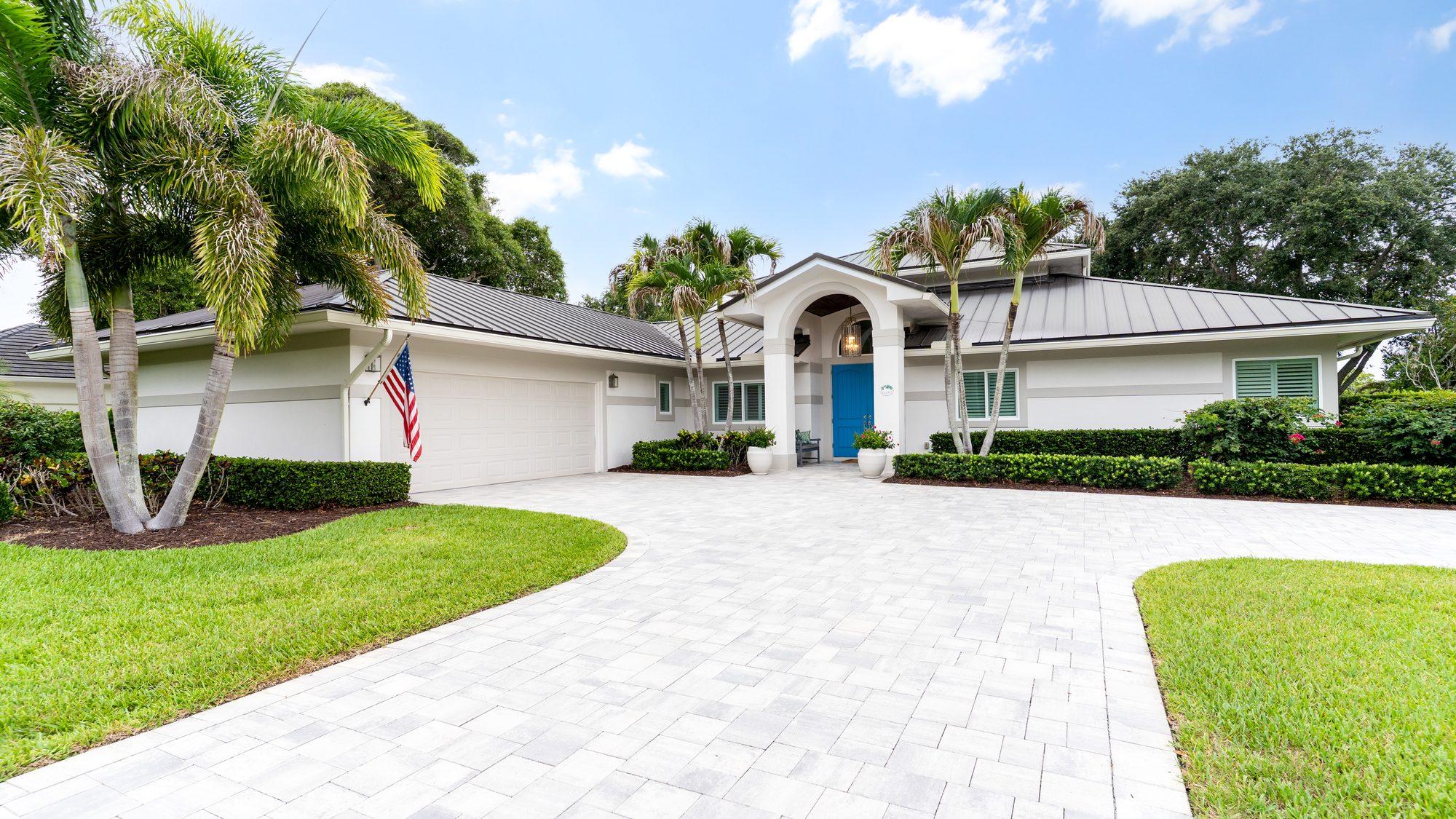 Front exterior with paver driveway and palm trees